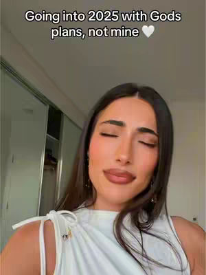 A woman with long brown hair, wearing a white top, has her eyes closed and a slight smile. Overlaid text indicates a focus on God's plans and the year 2025.