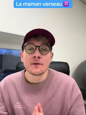 A man in glasses and a cap is in the cover. Above his head is an overlay with the text "La maman verseau" inside a blue box. The rest of the frame is a room, where a pillow and the wall are visible.