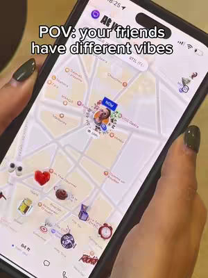 A phone displaying a map with location pins, held by a person with dark nail polish. Text overlay on the top states 'POV: your friends have different vibes'.