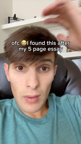 A selfie-style shot featuring a young man addressing the camera with a slightly surprised expression. Overlay text at the top says 'ofc 😭 I found this after my 5 page essay'. The background appears to be a neutral-toned interior.