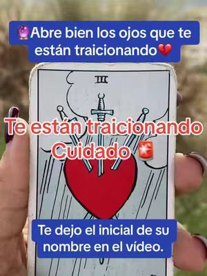 The image shows a hand holding a tarot card that has a red heart pierced by three swords on it. The card has white and black lines. On the top, there is a blue rectangular box with text, and the hand of the person holding the card is visible. Below and above the main card text are also present.