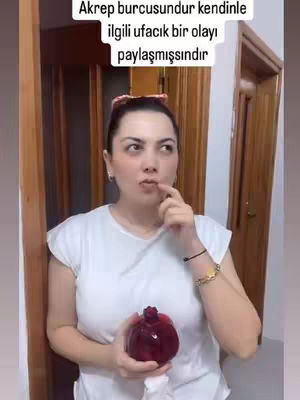 A woman in a white shirt is shown in a medium shot, holding a red object and looking upwards thoughtfully. Text overlayed on the top reveals the content is about zodiac signs.