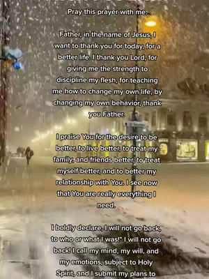 The image shows a snowy cityscape with a written prayer overlaid. The prayer text is the most prominent element, appearing in a white font against the background of buildings, streetlights, and falling snow. A few figures are walking in the distance.