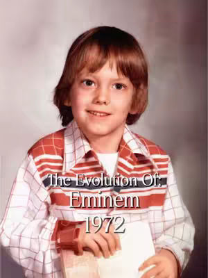 An image of Eminem as a young boy, circa 1972. He is wearing a red and white patterned shirt, and looking directly at the camera with a slight smile. Text overlayed on the image reads "The Evolution Of: Eminem 1972".