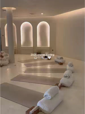 A bright, minimalist yoga studio interior featuring rows of yoga mats and bolsters, suggesting a space for wellness and self-improvement.