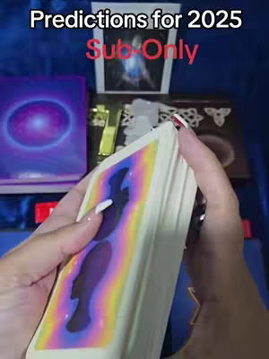 A person's hands holding a deck of tarot cards in front of a variety of decorative items. The person has long nails with white polish. The top of the image has the text 'Predictions for 2025 Sub Only'. The cards feature a black and blue silhouette on a rainbow gradient.
