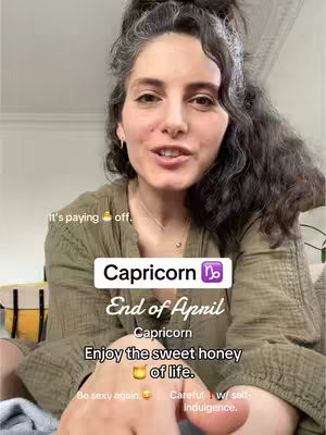 A woman with dark, wavy hair and a high bun is centered in the frame, speaking directly to the camera. Overlayed text gives astrological information. The background is a softly lit interior.