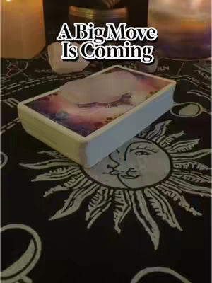 The cover image shows a tarot card deck resting on a black cloth. The cloth has a sun design in white. The deck is white, with a colorful image on the top suggesting a cosmic scene. Above the deck, text in a stylized font reads "A Big Move Is Coming".