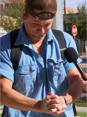 The cover image captures a man in a blue denim shirt with a black backpack standing outside with a microphone held towards him. He's wearing a brown baseball cap and a gold cross necklace, a ring on his finger and displaying a range of emotions and expressions as he looks downwards.