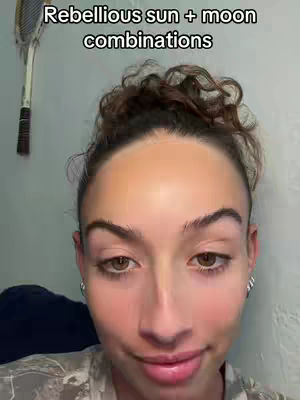 A selfie-style shot of a woman looking at the camera, the text overlay says "Rebellious sun + moon combinations". She's wearing a casual top, her dark hair is pulled back, and she has a neutral expression.