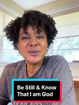 A woman with curly black hair and a gray shirt is centered in the frame, looking towards the camera. A colorful text box is superimposed, and the background includes windows and a glimpse of the outdoors, offering a soft, natural light.
