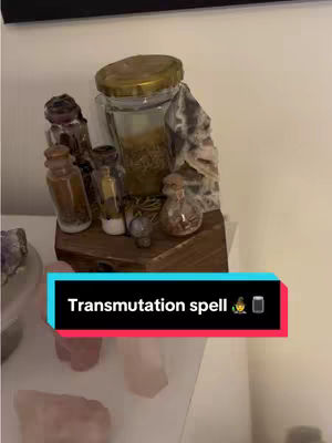 A well-lit indoor shot showing a collection of glass jars and bottles on a wooden shelf or stand. The jars contain what appears to be dried plant matter, spices, or herbs. The scene is further enhanced by a teal, black, and red text overlay towards the bottom with the text "Transmutation spell".