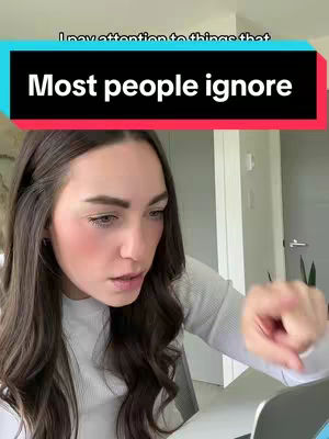 A woman with long brown hair is looking towards the bottom left corner of the image. She is wearing a gray long sleeve shirt and pointing her index finger to the right side. A rectangular text overlay is visible at the top of the frame.