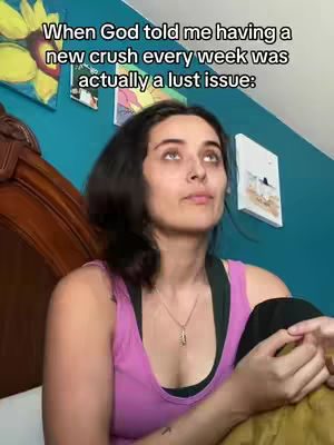 A woman in a pink tank top looks upwards with a thoughtful expression in a selfie-style shot. Text overlayed says "When God told me having a new crush every week was actually a lust issue:". Behind her is a teal wall with artwork and decorations.