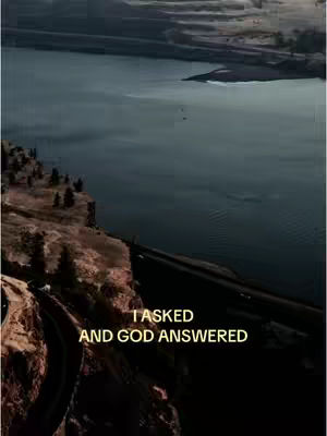 A scenic landscape image that appears to be an aerial view of a cliffside and a body of water. Overlay text in the image reads "I asked and God answered". The color palette is dominated by dark shades of blue, brown, and yellow.