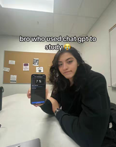 A woman is holding up a phone displaying a test score while looking at the camera in an office setting. Behind her is a bulletin board with several notes and a white wall. The text overlay reads 'bro who used chat gpt to study'.