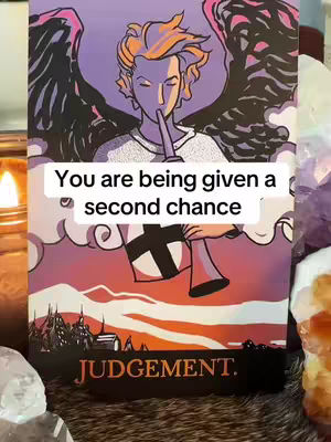 A tarot card showing an angel-like figure blowing a horn, with an overlay text. The card has a purple and orange color scheme with a background representing sky and clouds.