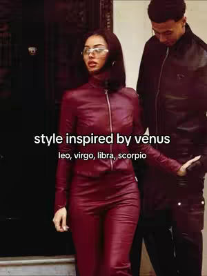 A woman in a maroon leather outfit is framed from the chest up with a dark-haired man on her right side. White text overlays the image, and the dark background, along with the outfit's color, creates a high-contrast visual