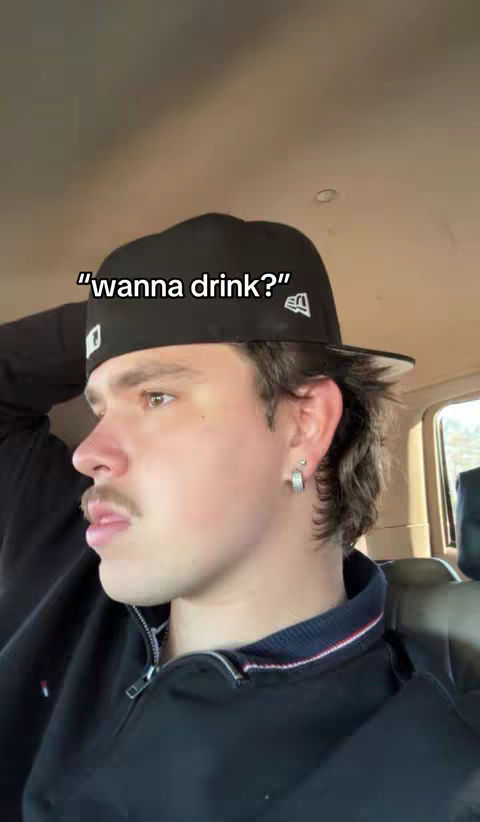 The cover image features a young man in a car, captured in profile. He wears a backward black cap and a black jacket with a zipper. The text overlay asks, \"wanna drink?\"