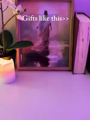 The cover image shows a framed picture of Jesus walking on water, placed on a white surface. There is a candle to the left and a book to the right. Decorative elements include an orchid branch. The background is softly lit with pink and purple hues.