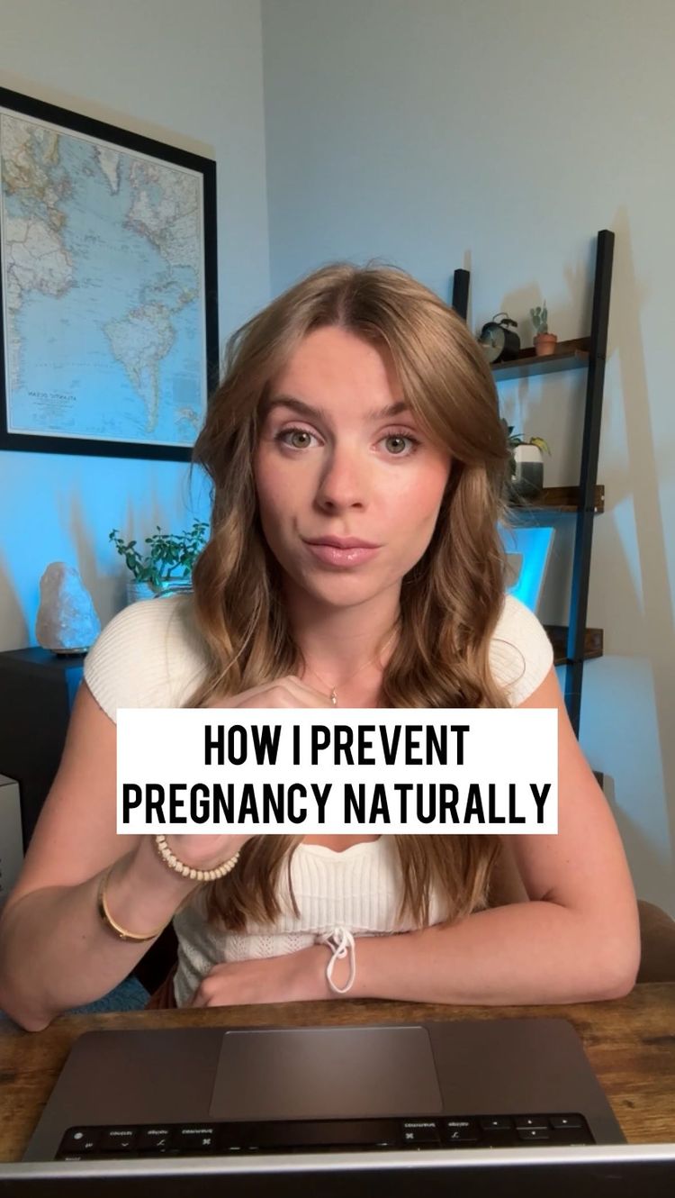 A woman with long blonde hair sits in front of a laptop, looking directly at the camera. Text overlay reads 'HOW I PREVENT PREGNANCY NATURALLY.' The background includes a world map, a shelf with various items, and a neutral wall color.