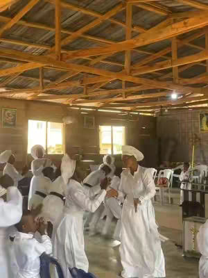 The cover image shows an indoor scene with a low wooden ceiling and several windows. Many people in white robes and head coverings are present. Some are facing each other while others seem to be dancing or moving around. The lighting is soft.