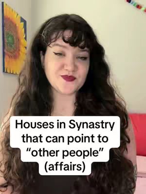 A woman with long, wavy dark hair and dark lipstick is centered in the frame. She is smiling slightly and looking towards the camera. Behind her, a painting of a sunflower and a red pillow can be seen. In front of her is a white text box that says, "Houses in Synastry that can point to 'other people' (affairs)".