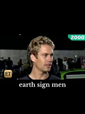 The image shows a man with blond hair in front of a background of a street with other people standing around. Below the man, there is text that reads "earth sign men".