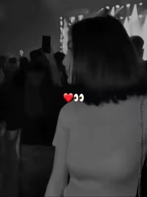 A black and white image of a person from the back, partially obscured. The person is in a crowded area, possibly a concert or event. Two emoji are placed near their shoulder.