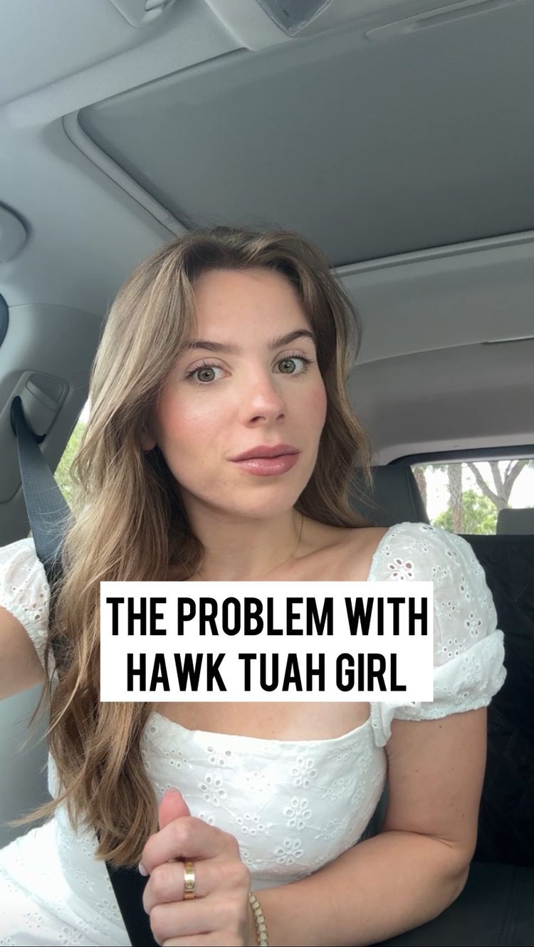 A woman seated in a car, framed from the chest up. She has long, wavy blonde hair. The car interior is visible, including the roof and a seatbelt. The woman is looking directly at the camera with a neutral expression. A white rectangular text overlay at the bottom of the frame reads, "THE PROBLEM WITH HAWK TUAH GIRL" in bold, white font.