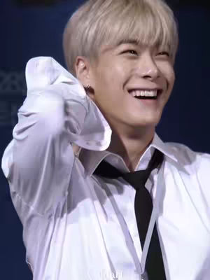 A close-up shot features a fair-skinned, blonde-haired man smiling broadly. He is wearing a white shirt and a black tie. The image has a warm, inviting feel with a focus on the man's positive expression.