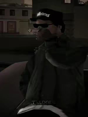 The image showcases a scene from the Grand Theft Auto: San Andreas game, with Ryder in the foreground wearing sunglasses and a hat. The background is blurred, depicting urban surroundings, enhancing the focus on the character. The overall color scheme is dark, giving a sense of grittiness.