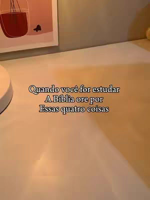 The cover image shows a close-up view of a beige surface, possibly a tabletop or desktop. Text in the center of the image reads, 'Quando você for estudar A Bíblia ore por Essas quatro coisas' (When you study the Bible, pray for these four things). In the background, a portion of a framed artwork with a dark red object is visible. The lighting is soft, casting slight shadows.