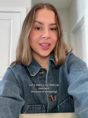 A young woman with long blonde hair and wearing a denim jacket looks directly at the camera, smiling. Text overlayed on the image states, Let's make a $2,000 car payment (instead of shopping).