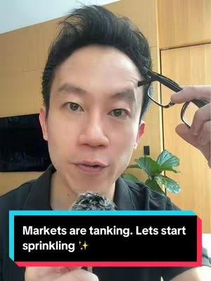 A man in a black shirt is holding glasses near his face while looking at the camera. Text overlayed in a black box at the bottom of the image says 'Markets are tanking. Lets start sprinkling✨'. The background is a neutral-toned wall with a small plant visible.
