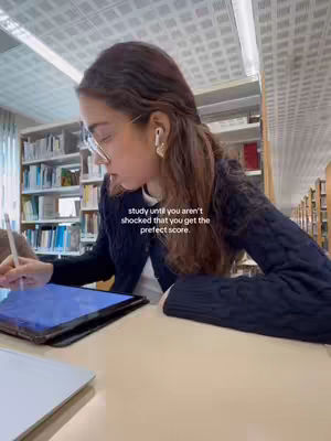 A woman in a library setting is working on a tablet, with a quote overlayed about studying. The image is lit with natural light from a window, and shelves of books fill the background.