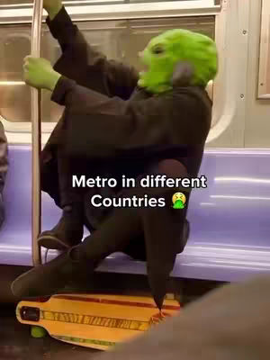 A person wearing a green alien mask is seated on a subway car seat holding onto a pole. The subway car has a purple seat and a yellow-colored skateboard is on the floor. Text overlayed at the bottom of the image states \"Metro in different Countries\".