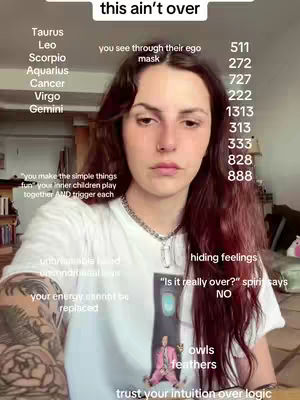 A person with long auburn hair, wearing a white t-shirt and a necklace, is the central figure. Text overlays include astrological signs, numerical codes, and phrases like 'this ain't over' and 'trust your intuition over logic'. The background is a softly lit indoor setting.