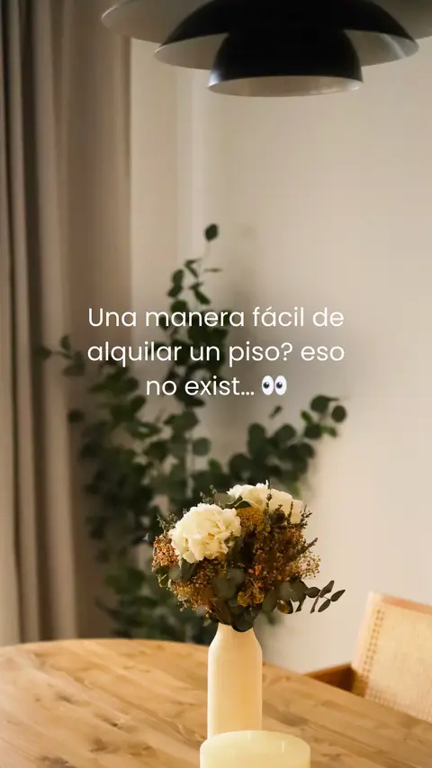 A well-lit interior shot focusing on a wooden table, adorned with a vase of flowers. The lighting and composition are soft and inviting, with a blurred green plant in the background. Text is overlaid on the image in a clean, modern font.