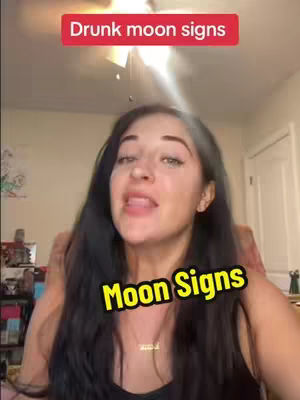 A woman with long dark hair is centered in the frame, looking towards the camera. Above her head is red bar that says "Drunk moon signs" with white text. At the bottom is another text box with yellow text that says "Moon Signs". The background blurs to show a generic interior.