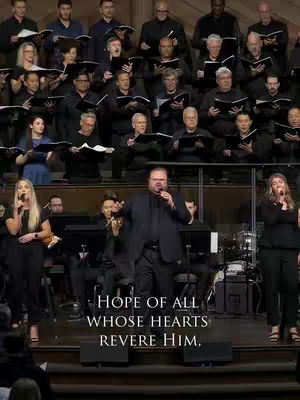 The cover image shows a choir and soloists performing in a well-lit church. The background features a large group of people, predominantly men, in formal attire, holding sheet music. In the foreground, a man, in a black suit, stands as a soloist. Two women stand with mics on either side of him. Below them, text is overlaid with the words: 'HOPE OF ALL WHOSE HEARTS REVERE HIM,' in a white sans-serif font.