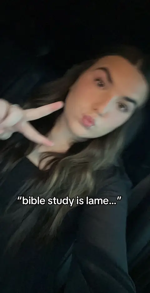 A selfie-style shot featuring a young woman in a dark setting, possibly inside a vehicle. She's making a peace sign with her left hand held up near her face and a kissing face with her lips. The background is dark, and the lighting appears to be from an interior source. There is text overlay on the image that reads bible study is lame.