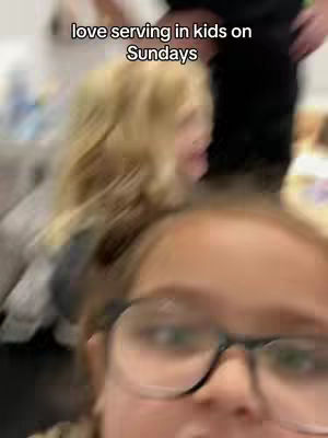 A selfie-style image with a blurred foreground, featuring a person wearing glasses, with a young girl partially visible behind them. The top of the image has the text overlayed.