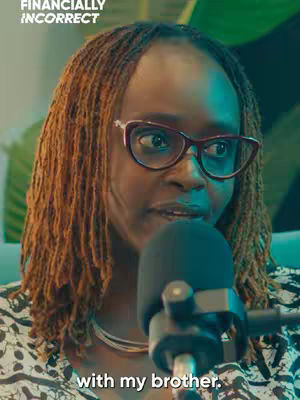 A woman with locs and glasses is centered in the frame, speaking with a microphone. The background is out of focus. Text overlays read, Finacially Incorrect and 'with my brother.'
