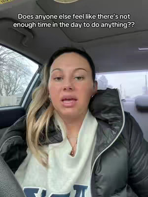 A woman with blonde hair is sitting in the driver's seat of a car, looking at the camera and speaking. Text overlayed at the top reads: "Does anyone else feel like there's not enough time in the day to do anything??"