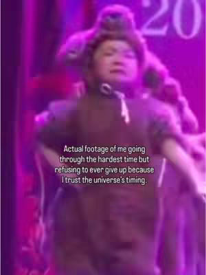 The cover image shows a blurry figure in what appears to be a performance setting, illuminated by purple lighting. Text overlayed on the image states, "Actual footage of me going through the hardest time but refusing to ever give up because I trust the universe's timing."