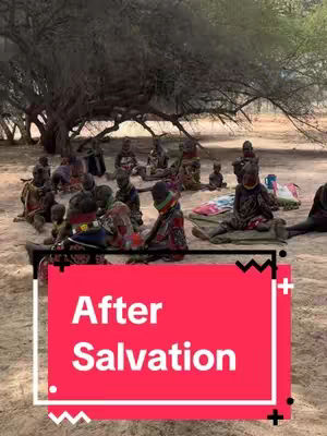 A group of people, likely of African descent, are gathered outdoors, possibly under a large tree. The scene seems to be a meeting or gathering. An overlay on the image has text over a red rectangle.