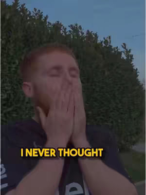 A man with red hair is shown from the chest up against a backdrop of green foliage and a blue sky. He has his hands covering his face, suggesting emotion or surprise. The overlay reads 'I NEVER THOUGHT' in yellow, hinting at the video's theme.