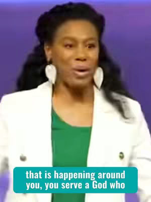 A medium shot features a Black woman centered in the frame, set against a purple backdrop. She is wearing a white blazer over a green top, with large, heart-shaped earrings. Her expression is animated and her mouth is open as if she is speaking. A light blue rectangular text overlay is at the bottom of the image.