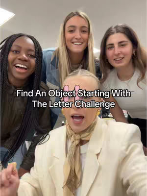 A group of four young women are gathered closely together, smiling at the camera. The image has a well-lit, slightly blurred background. The top is where the words 'Find An Object Starting With The Letter Challenge' appear on the image.